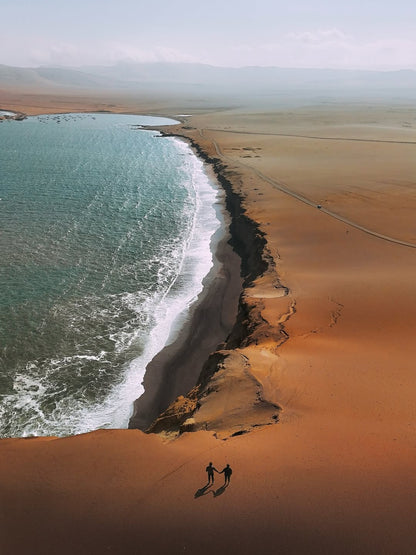 Falaises désertiques de la réserve nationale de Paracas sur la côte du Pacifique au Pérou avec vagues frappant la plage.