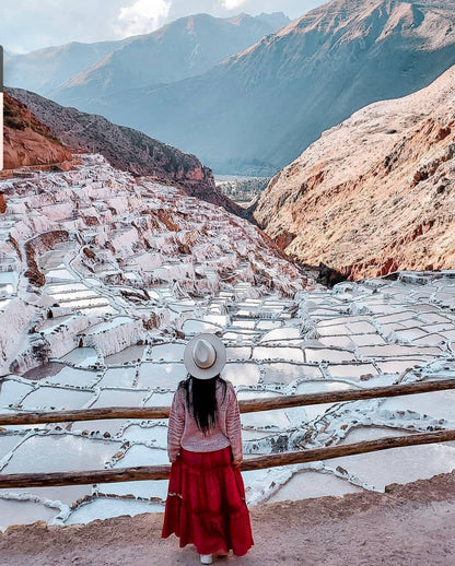Vue des marais salants de Maras dans la vallée sacrée près de Cusco au Pérou avec une visiteuse observant les bassins de sel.