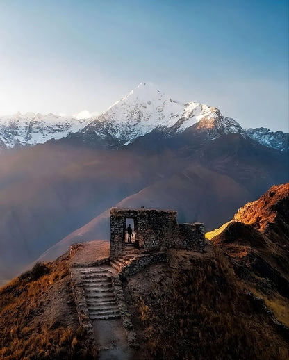 Ancienne structure en pierre servant de mirador avec vue sur une montagne enneigée dans les Andes du Pérou.