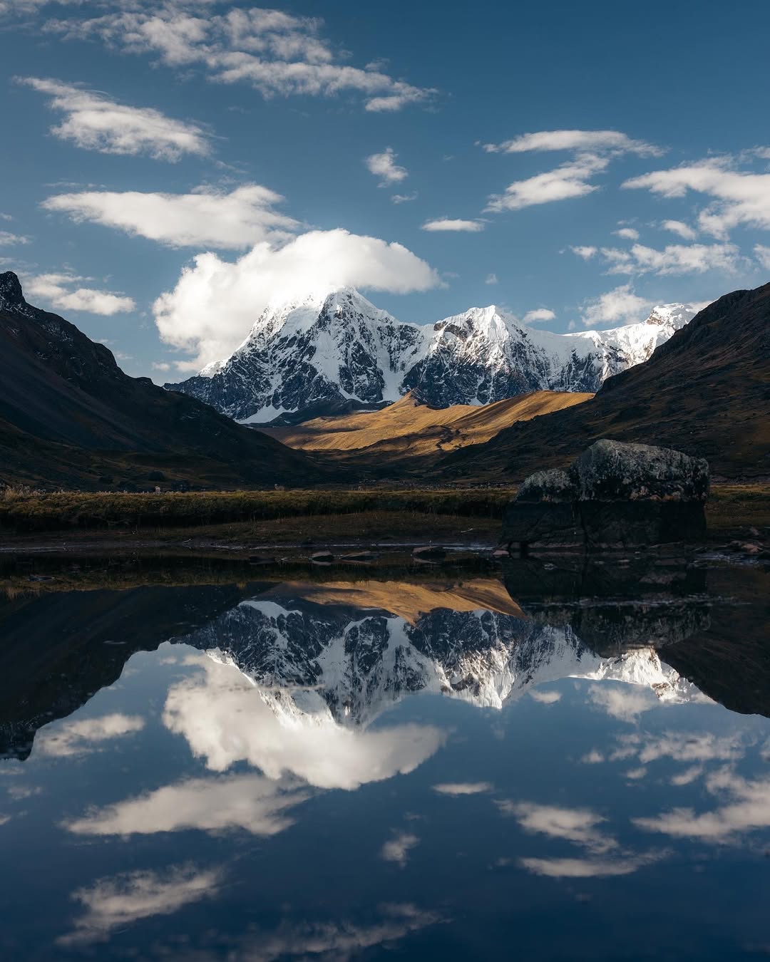 Montagnes enneigées des Andes se reflétant dans une lagune calme sous un ciel bleu au Pérou.