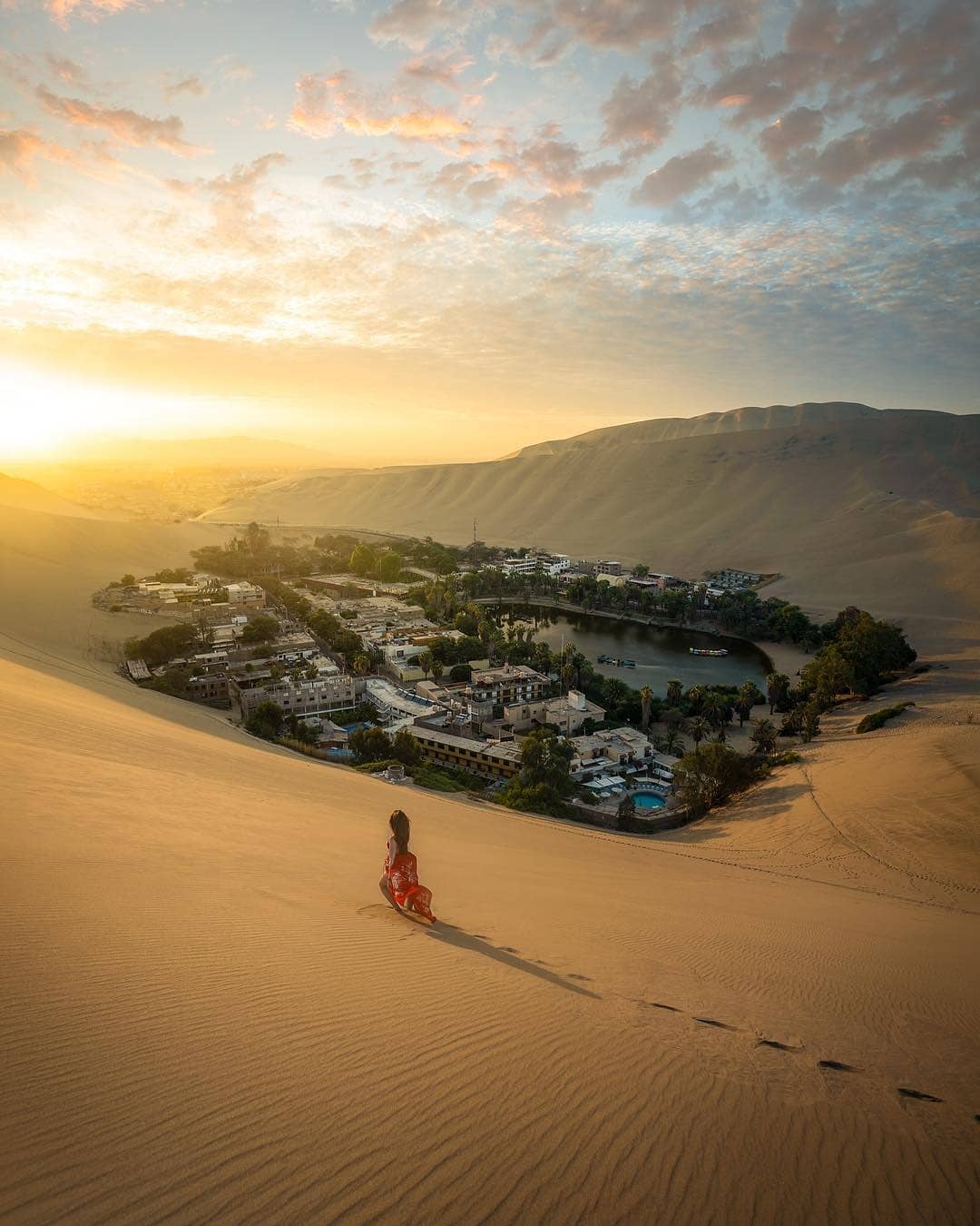 Vue de l’oasis de Huacachina entourée de grandes dunes de sable dans le désert d’Ica au coucher du soleil au Pérou.