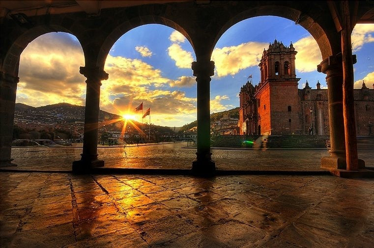 Vue de la Plaza de Armas de Cusco et de la cathédrale depuis les arcades au coucher du soleil au Pérou.