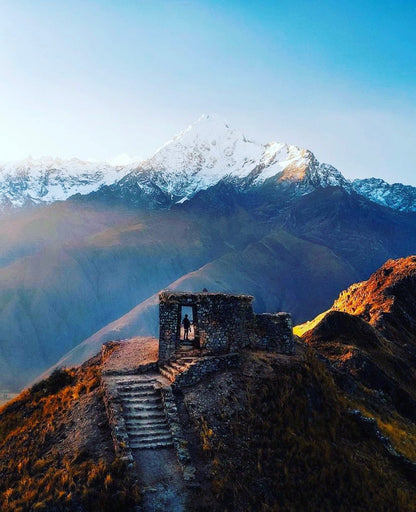 Anciennes ruines incas sur une colline avec vue sur une montagne enneigée dans les Andes du Pérou.